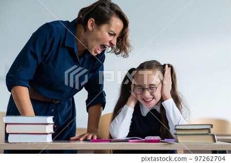 A female teacher yells at a student. Little girl covers her ears with her hands. 97262704