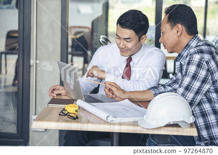 Contractor construction engineer meeting talking together on architect table at construction office site. Businessman engineer manager discuss with foreman team builder look at plan blueprint laptop 97264870