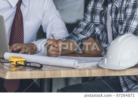 Contractor construction engineer meeting talking together on architect table at construction office site. Businessman engineer manager discuss with foreman team builder look at plan blueprint laptop 97264871