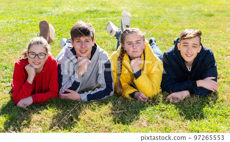 Group of positive teenagers lying on green grass Group of positive teenagers lying on green grass 97265553