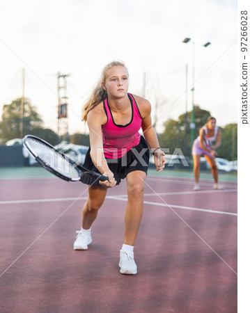 Sporty teenage girl tennis player playing tennis at court. View through tennis net 97266028