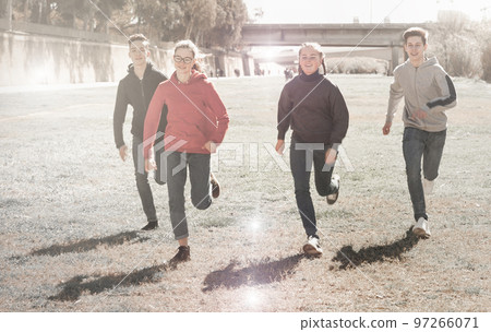 Cheerful teens running on green lawn 97266071
