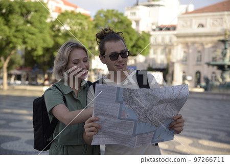 Smiling tourist couple checking map Smiling tourist couple checking map 97266711