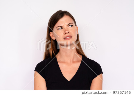 Portrait of uncertain young woman looking away and frowning Portrait of uncertain young woman looking away and frowning 97267146