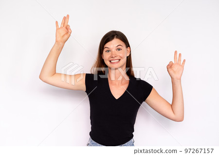 Portrait of excited young woman making ok gesture 97267157