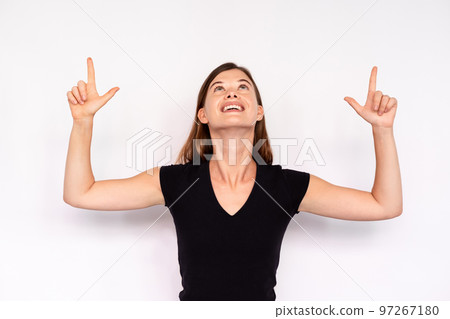 Portrait of excited young woman pointing upwards 97267180