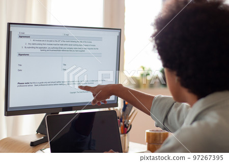 Female office worker working on computer and pointing at screen Female office worker working on computer and pointing at screen 97267395