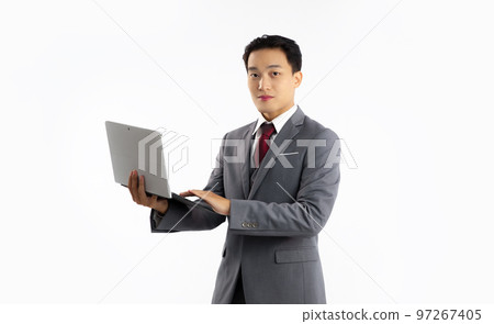 Young asian businessman in grey suit red tie standing holding and using laptop computer looking camera on white background.. 97267405