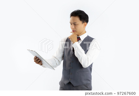 Asian businessman in grey suit holding tablet looking and reading white background.. 97267600