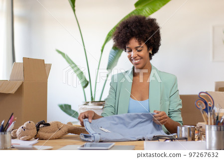 Smiling black woman folding clothes for dispatch 97267632