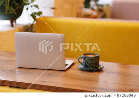 Laptop and a cup of coffee on a wooden table in a coffee shop Laptop and a cup of coffee on a wooden table in a coffee shop 97269049