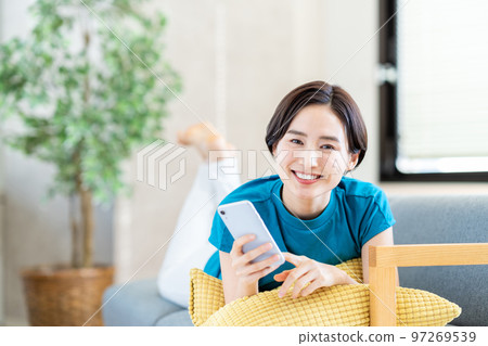 A woman who manipulates a smartphone in the living room A woman who manipulates a smartphone in the living room 97269539