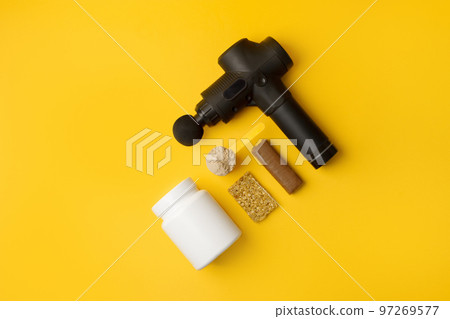 Therapeutic percussive massage gun, fit meal, pills, sport energy bar, protein on yellow background - concept of modern sport activity and diet, health lifestyle routine, wellness, healthcare Therapeutic percussive massage gun, fit meal, pills, sport energy bar, protein on yellow background - concept of modern sport activity and diet, health lifestyle routine, wellness, healthcare 97269577