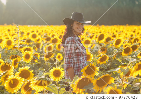 Young woman farmer on sunflower field. Harvesting and farming concept 97270428