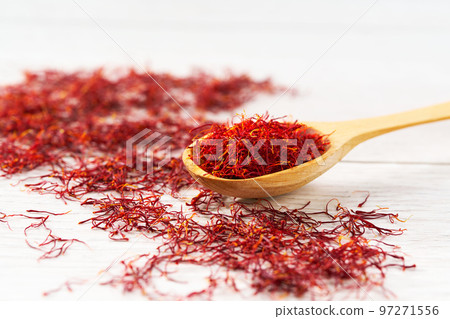 Dried saffron spices in a wooden spoon on a white table, selective focus. Dried saffron spices in a wooden spoon on a white table, selective focus. 97271556