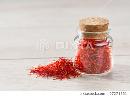 Dried saffron spices in a bottle on a wooden table. 97271561