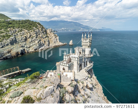 Crimea Swallow's Nest Castle on the rock over the Black Sea. It is a tourist attraction of Crimea. Amazing aerial view of the Crimea coast with the castle above abyss on sunny day. Crimea Swallow's Nest Castle on the rock over the Black Sea. It is a tourist attraction of Crimea. Amazing aerial view of the Crimea coast with the castle above abyss on sunny day. 97271611
