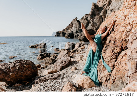 Side view a Young beautiful sensual woman with black hair in a long mint dress posing on a beach with calm sea bokeh lights on sunny day. Girl on the nature on blue sky background. Fashion photo Side view a Young beautiful sensual woman with black hair in a long mint dress posing on a beach with calm sea bokeh lights on sunny day. Girl on the nature on blue sky background. Fashion photo 97271617