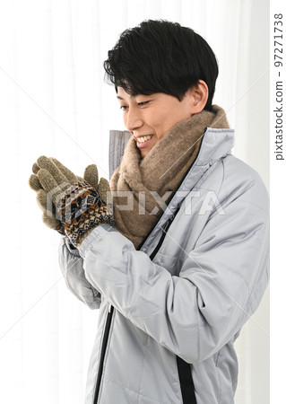 A young man wearing a coat and wearing a muffler and gloves 97271738