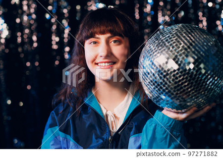 Young sporty woman 80 and 90's style. 90s fashion positive girl at night club disco party with disco ball Young sporty woman 80 and 90's style. 90s fashion positive girl at night club disco party with disco ball 97271882