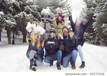 Portrait of group of happy men and women having fun and playing with snow in winter forest. 97273546