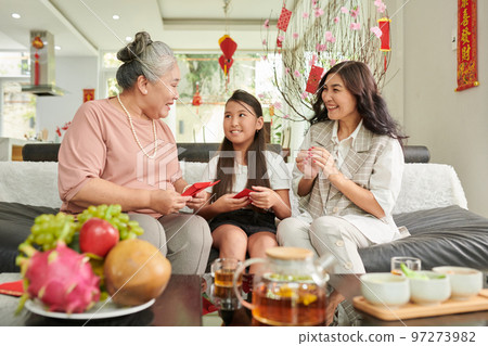 Happy senior woman gifting lucky money envelopes to daughter and granddaughter 97273982