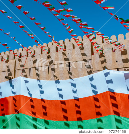 Oman national flag during Independence Day. Traditional medieval architecture in Nizwa, Oman.  97274466