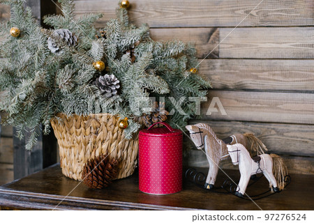 A souvenir horse, a raspberry tin can against a background of fir branches in a wicker basket. Christmas decor A souvenir horse, a raspberry tin can against a background of fir branches in a wicker basket. Christmas decor 97276524