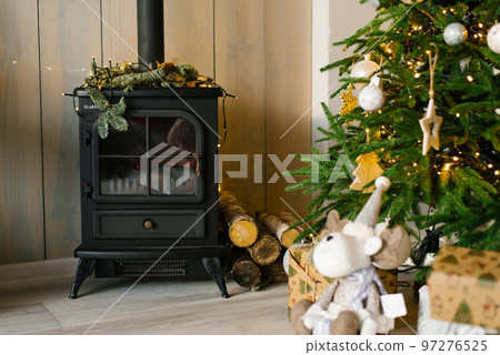 Classic cast iron fireplace with wood and Christmas tree Classic cast iron fireplace with wood and Christmas tree 97276525
