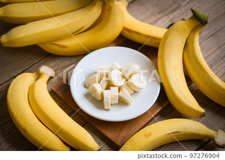 bunch of bananas - banana sliced on wooden background, ripe banana peel fruit on floor 97276904