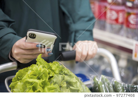 在超市用智能手機購物的年輕女子的手 97277408