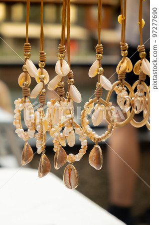 Jewelery showcase sea decorations on street market. Woman choosing decorations on local street market in Gdansk, Poland. Female tourist is choosing souvenirs in street shop and looking at color 97277690