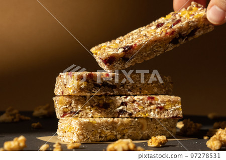 Woman takes Homemade Granola energy bar. Variety of protein granola breakfast bars, with nuts, raisins dried cherries and chocolate. Healthy nutrition eating Gluten free cereal dieting snack super Woman takes Homemade Granola energy bar. Variety of protein granola breakfast bars, with nuts, raisins dried cherries and chocolate. Healthy nutrition eating Gluten free cereal dieting snack super 97278531
