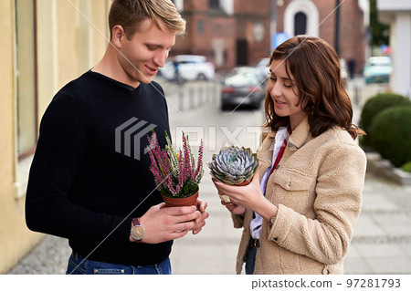 Man and woman holding a purple sempervivum succulent plant and blooming violet heather plant Man and woman holding a purple sempervivum succulent plant and blooming violet heather plant 97281793