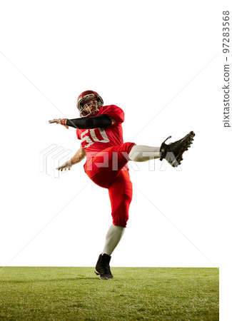 Kick the ball. Professional american football player in sports uniform and protective helmet training with ball isolated over white background. Sport, team, competition, championship 97283568