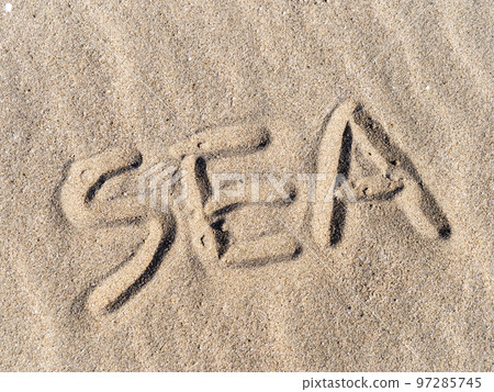 The letters "SEA" written on the sandy beach. 97285745