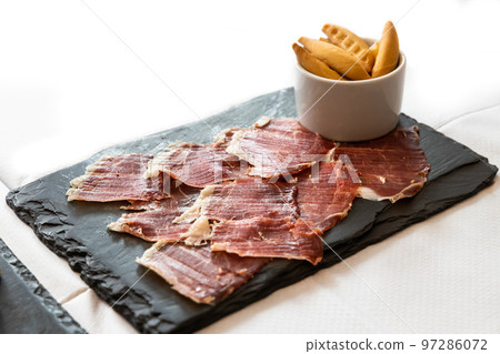 Delicious Iberico or Iberian ham served on a platter with crackers bread Delicious Iberico or Iberian ham served on a platter with crackers bread 97286072