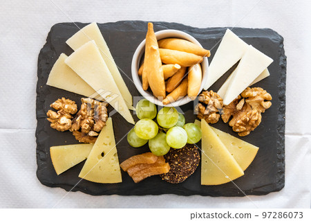 Overhead view on platter of cheese, cracker, nuts and grapes served on cheeseboard Overhead view on platter of cheese, cracker, nuts and grapes served on cheeseboard 97286073