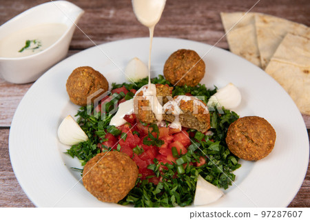Vegetarian dish, falafel balls from spiced chickpeas with chopped parsley, fresh onions and tomato 97287607