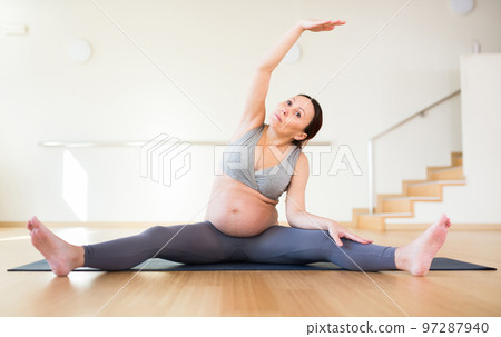 Pregnant woman is engaged in yoga. Revolved seated side angle pose or Parivrtta Upavistha Konasana 97287940
