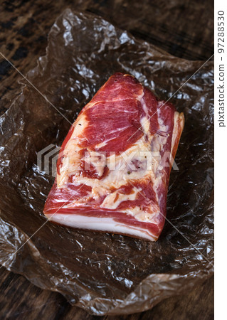 Smoked bacon on a wooden rustic table, natural product from organic farm, produced by traditional methods Smoked bacon on a wooden rustic table, natural product from organic farm, produced by traditional methods 97288530