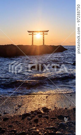 A torii standing by the sea with the sun in the background A torii standing by the sea with the sun in the background 97288750