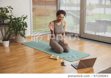 Afro american woman talking with fitness instructor by video call before online classes at home Afro american woman talking with fitness instructor by video call before online classes at home 97289063