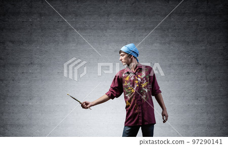 Young emotional artist gesturing with paintbrush 97290141