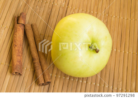 Ripe green Apple and cinnamon sticks on bamboo napkin Ripe green Apple and cinnamon sticks on bamboo napkin 97291298