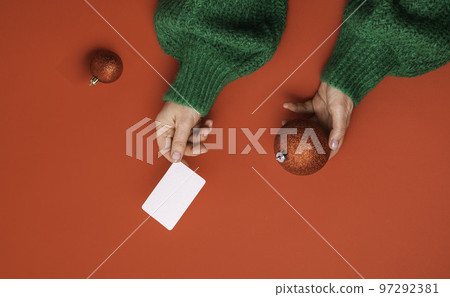Christmas shopping concept. Flat lie hands in a green sweater with bonus card. Banner on a red background Christmas shopping concept. Flat lie hands in a green sweater with bonus card. Banner on a red background 97292381