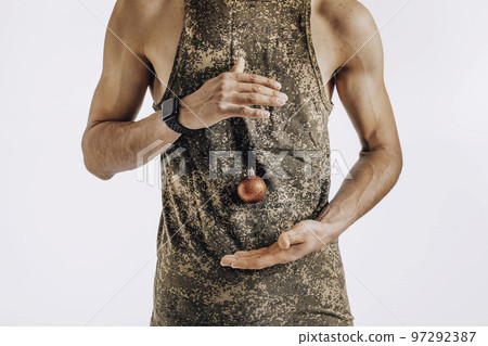 Christmas and the army. A golden Christmas ball hangs on the T-shirt of a young soldier standing on a white background 97292387