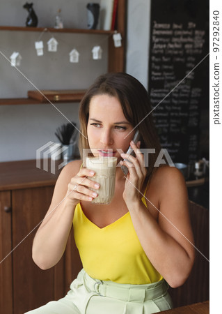 portrait of woman with cup of health drink in her hand and talking o smartphone portrait of woman with cup of health drink in her hand and talking o smartphone 97292840