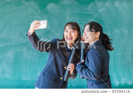 A high school student holding a diploma and taking a commemorative photo in the classroom 97294219