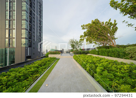 Sky garden on private rooftop of condominium or hotel, high rise architecture building with tree, grass field, and sunset sky. 97294431